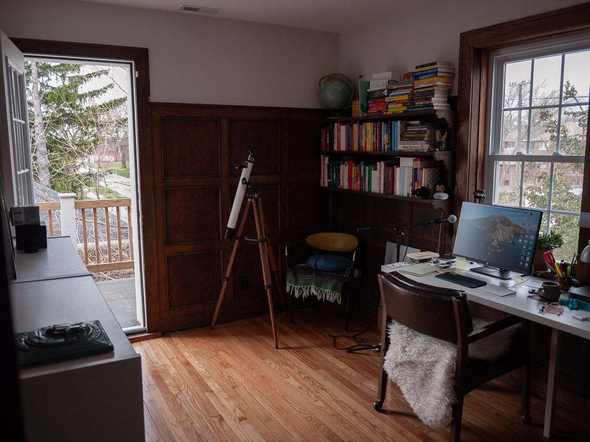 A desk, a screen, and stacks of books.