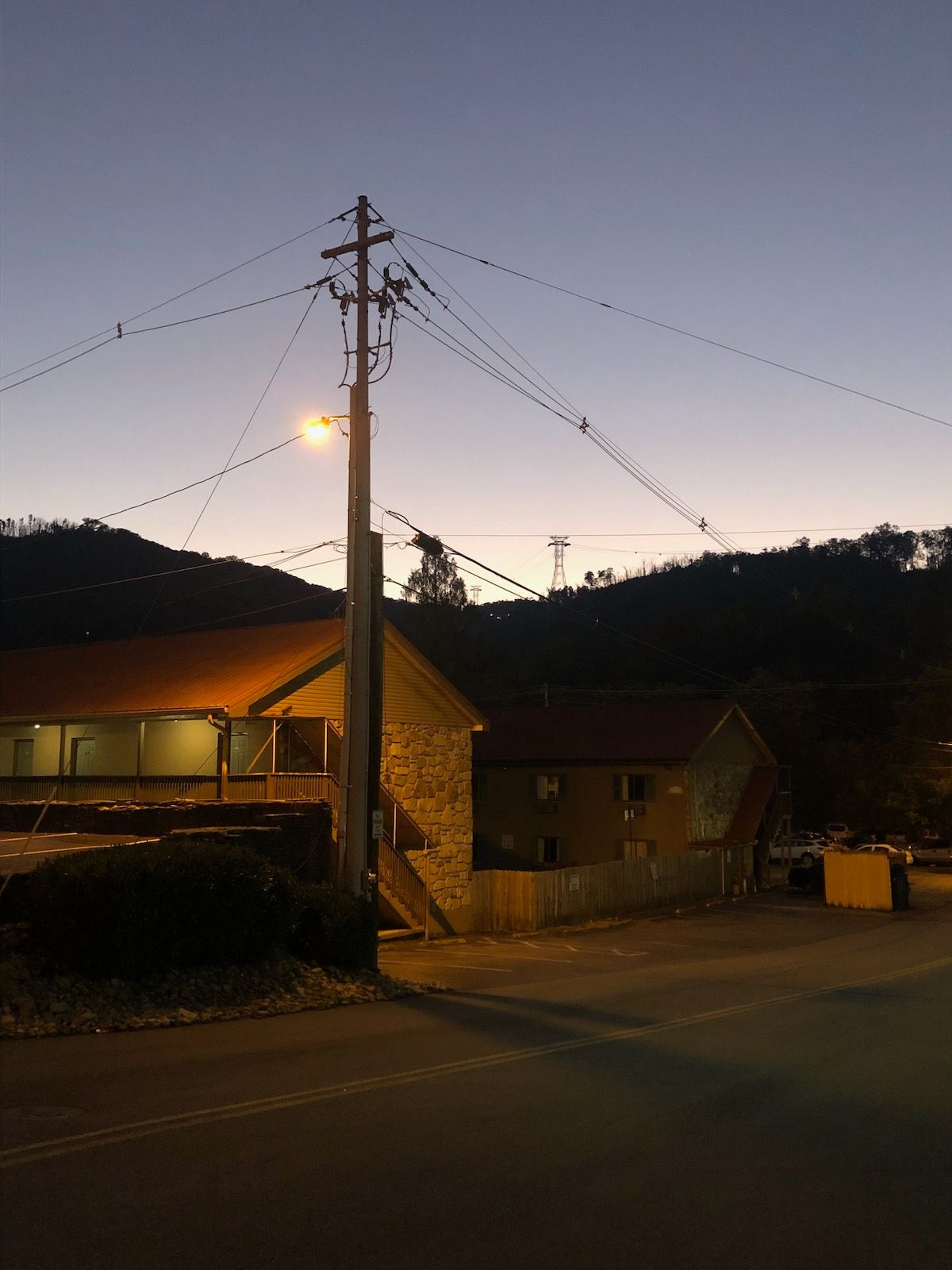 Empty, street, dimly lit houses, electrical pole.