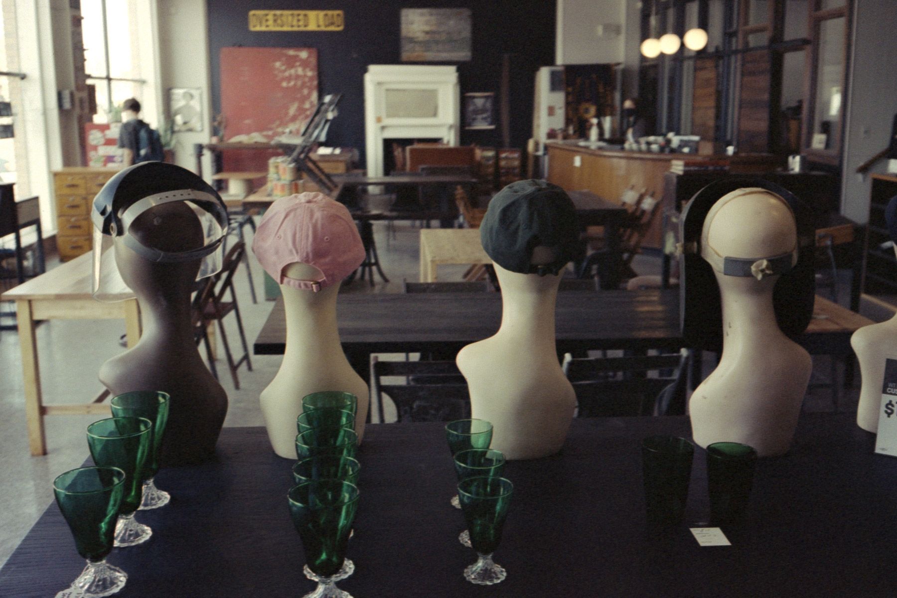 Row of vintage store masked and behatted mannequin heads, shot from behind.
