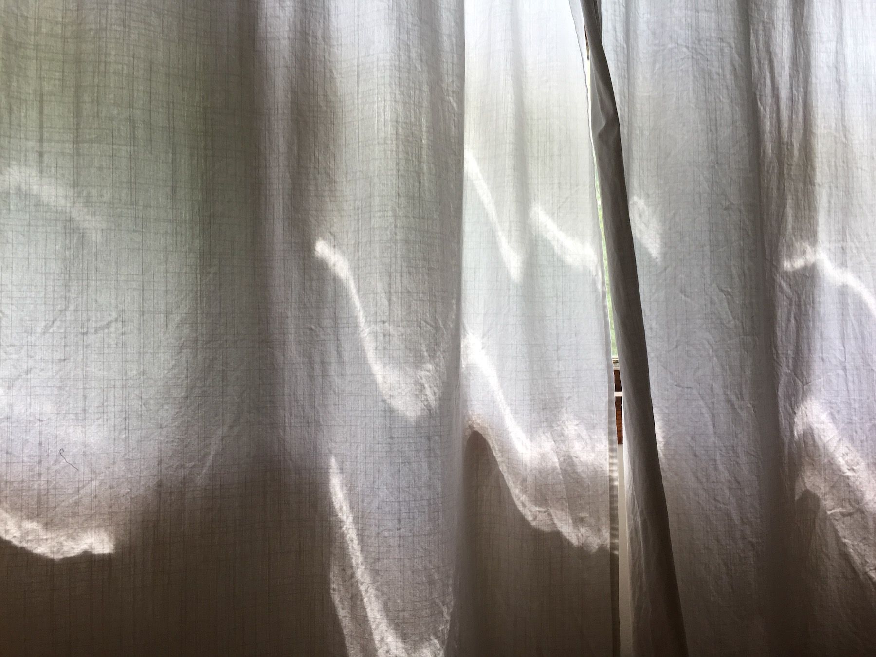 Ribbons of light on white linen curtains.