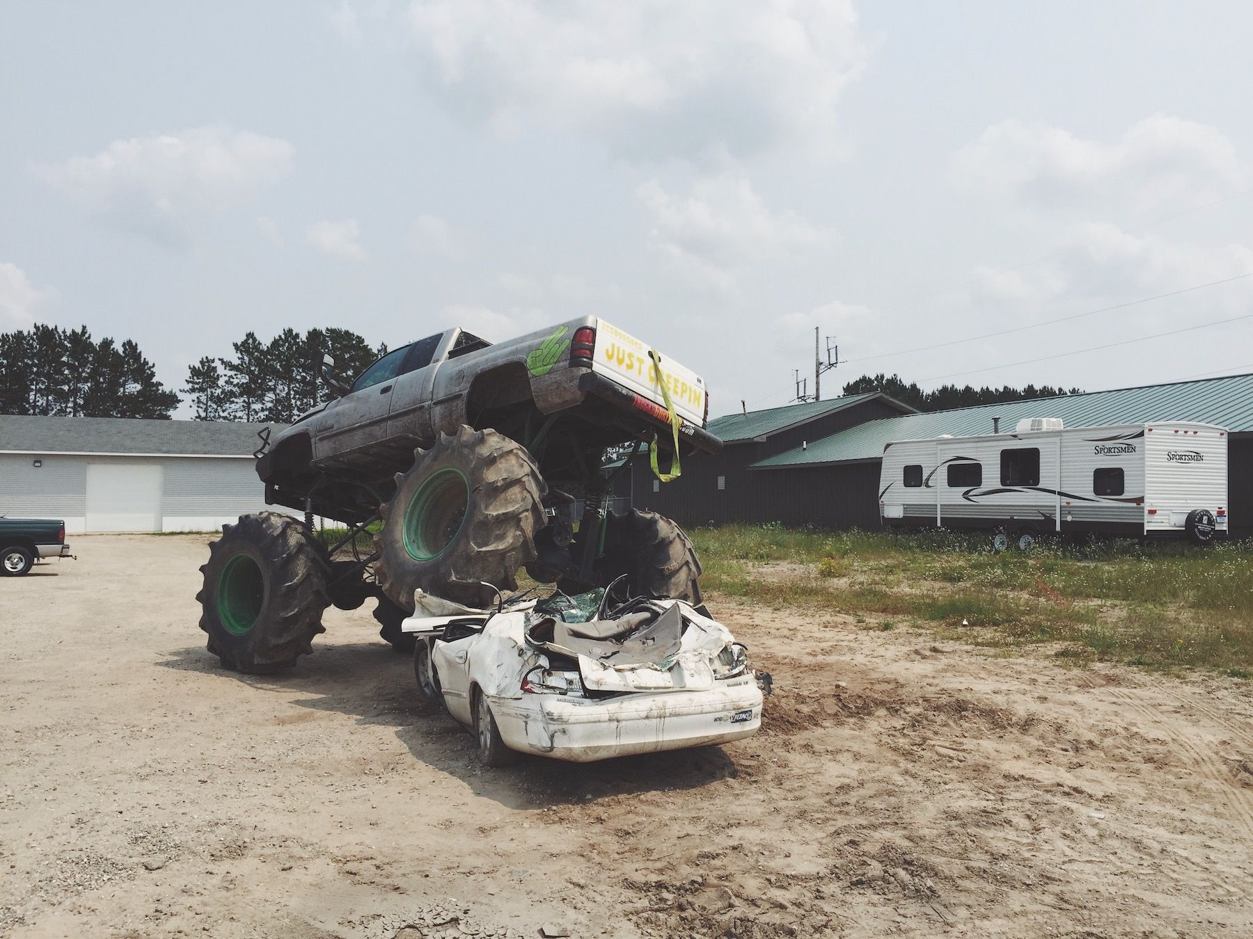 Monster truck mid-crush on old white car. Some kind of art installation?