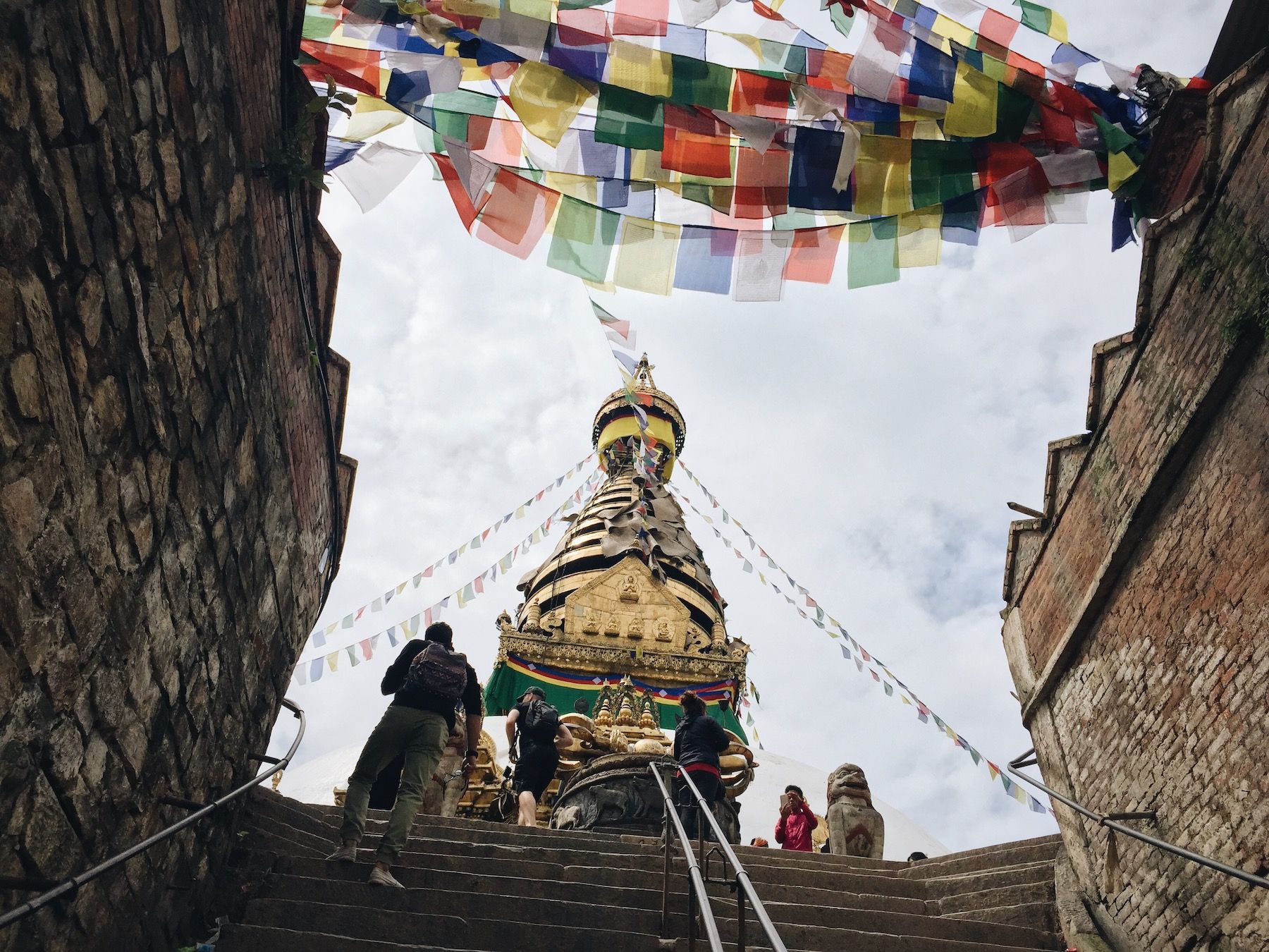 Looking up stairs at stupa. Colorful prayer flags.