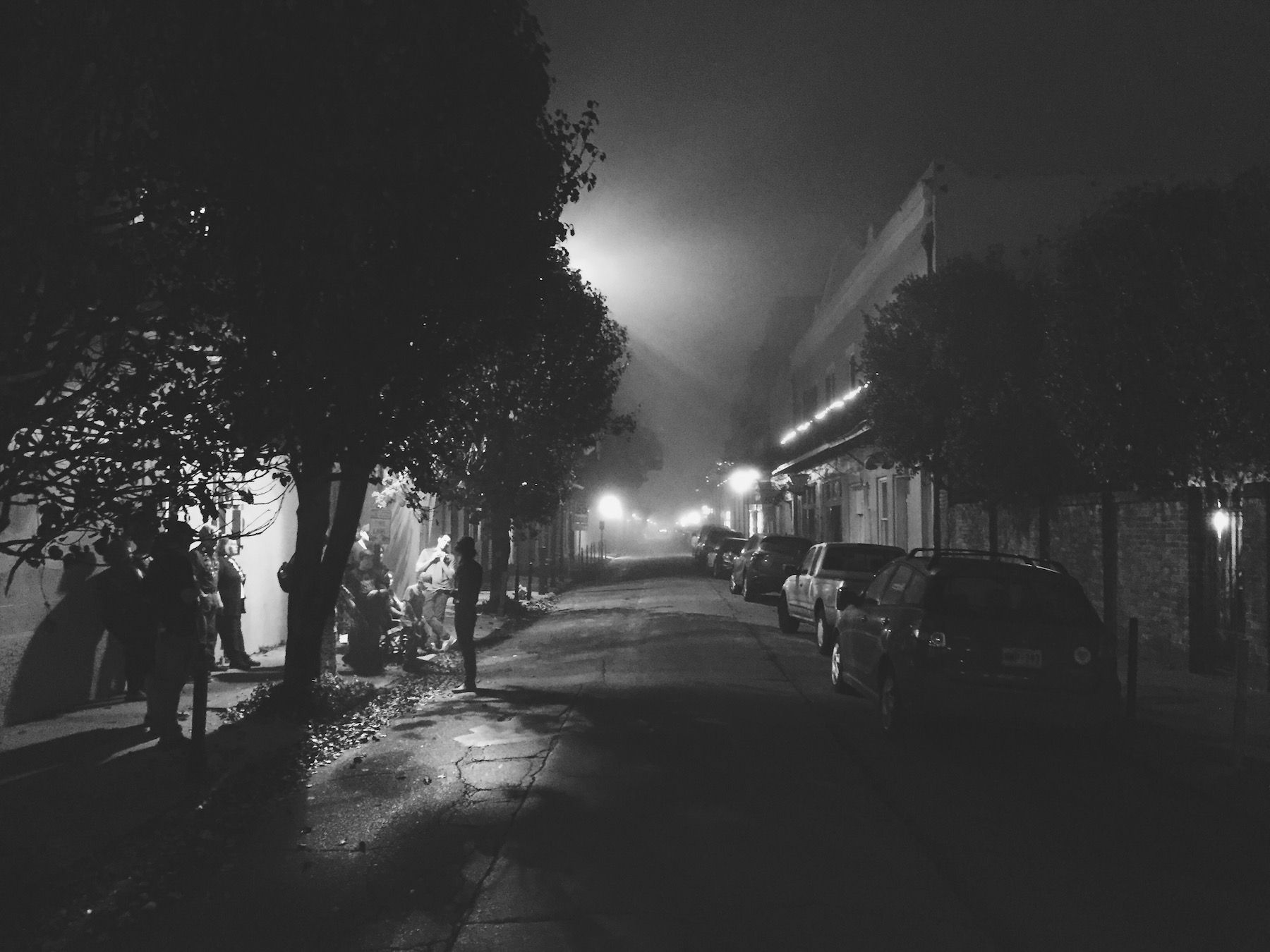 Foggy black and white. Group of ghost tourist under streetlamp.