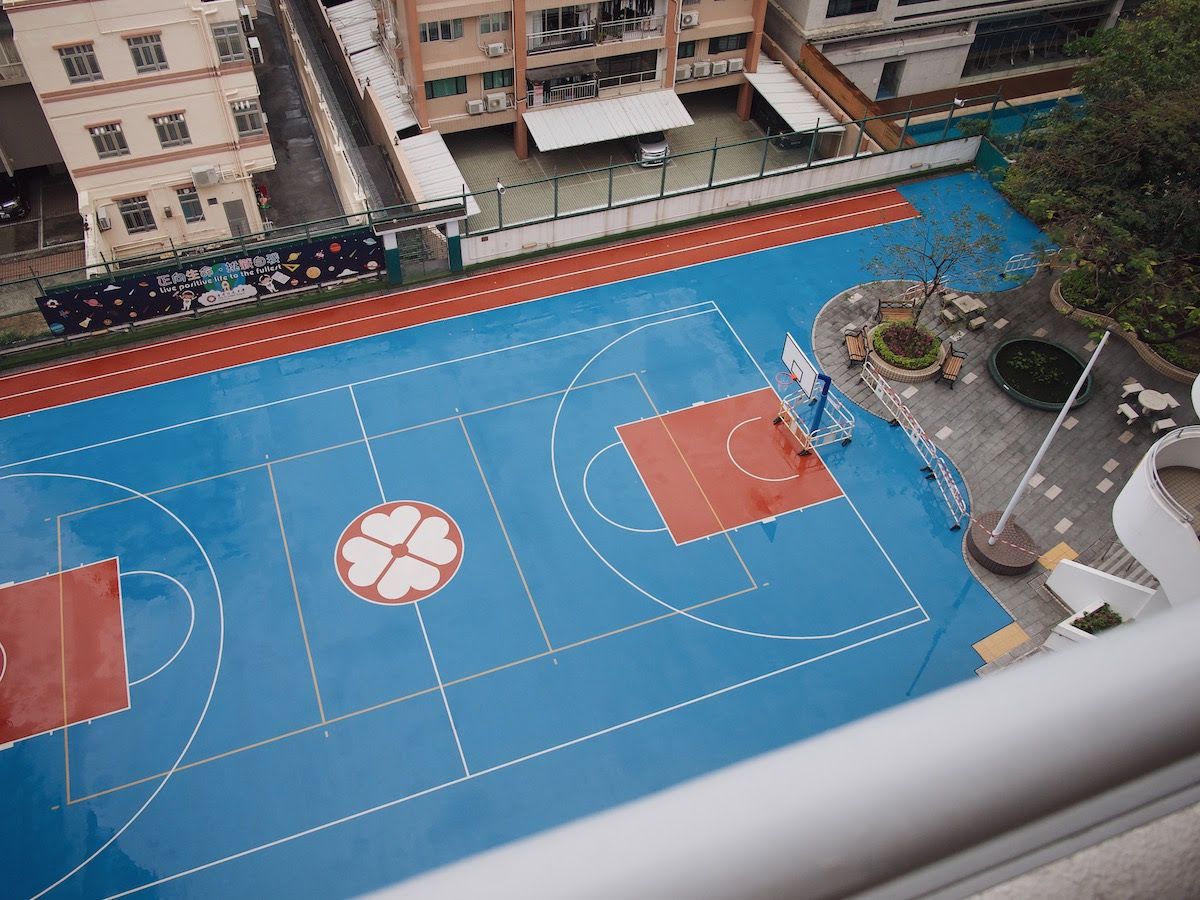 Empty blue basketball court, wet pavement.