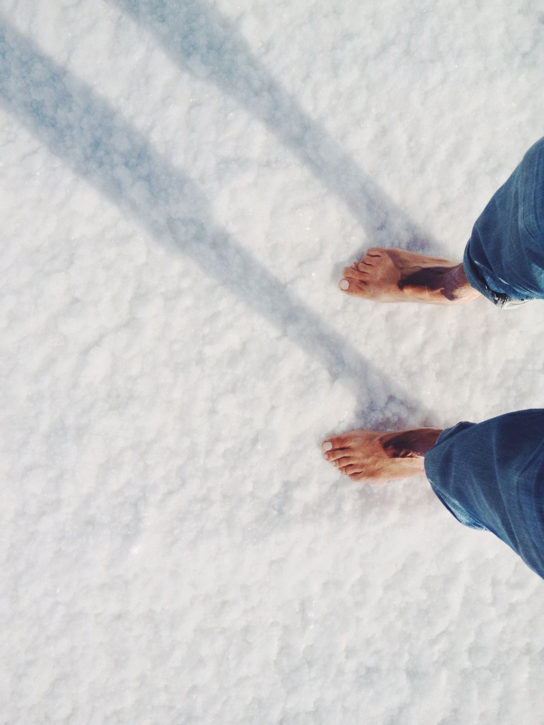 POV of bare feet on show-white salt.