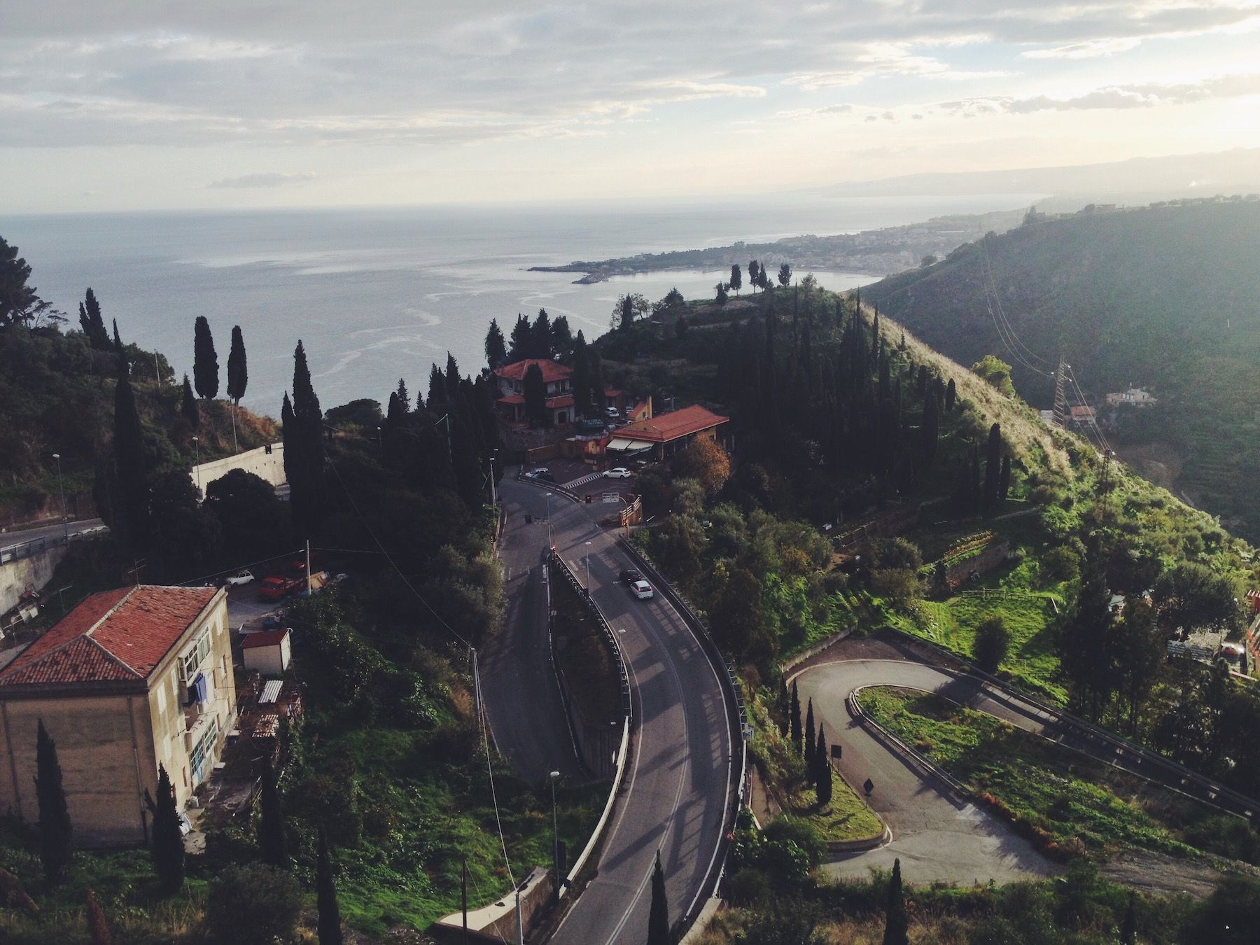 Hairpinned Mediterranean roads. Sea and green cliffs, terra cotta roofs.