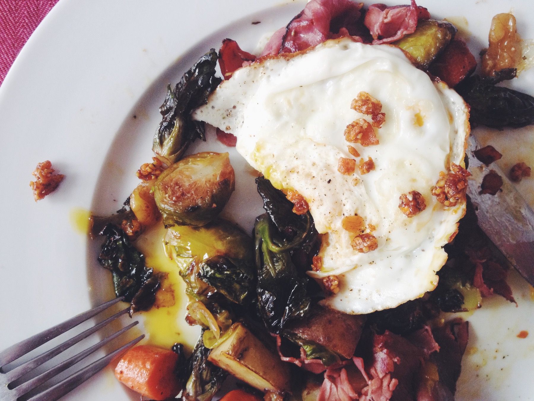 Breakfast plate: ham and eggs, carrots, Brussels sprouts, crunchy garlic topping. Fork tines in bottom left corner.