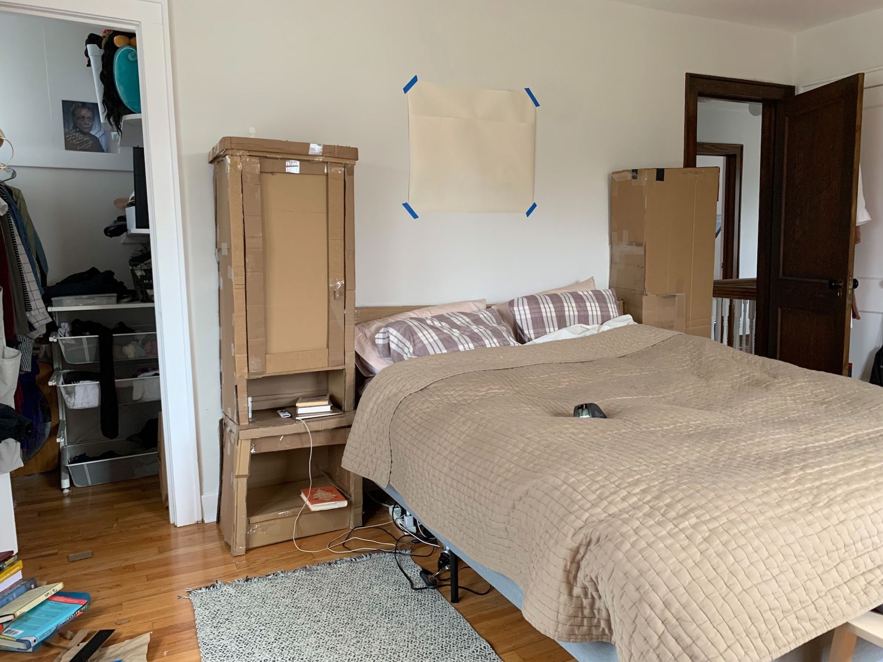 Full-size cardboard mockup of furniture project: two cabinets units and headboard at head of bed.