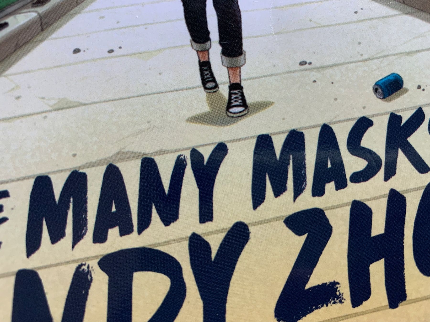 Close-up crop of cover with sneakers, pop can, and letters MANY MASK NDY ZH visible.