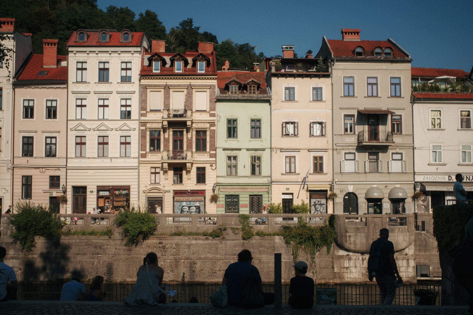 Colorful houses along riverfront, silhouettes of people at bottom.