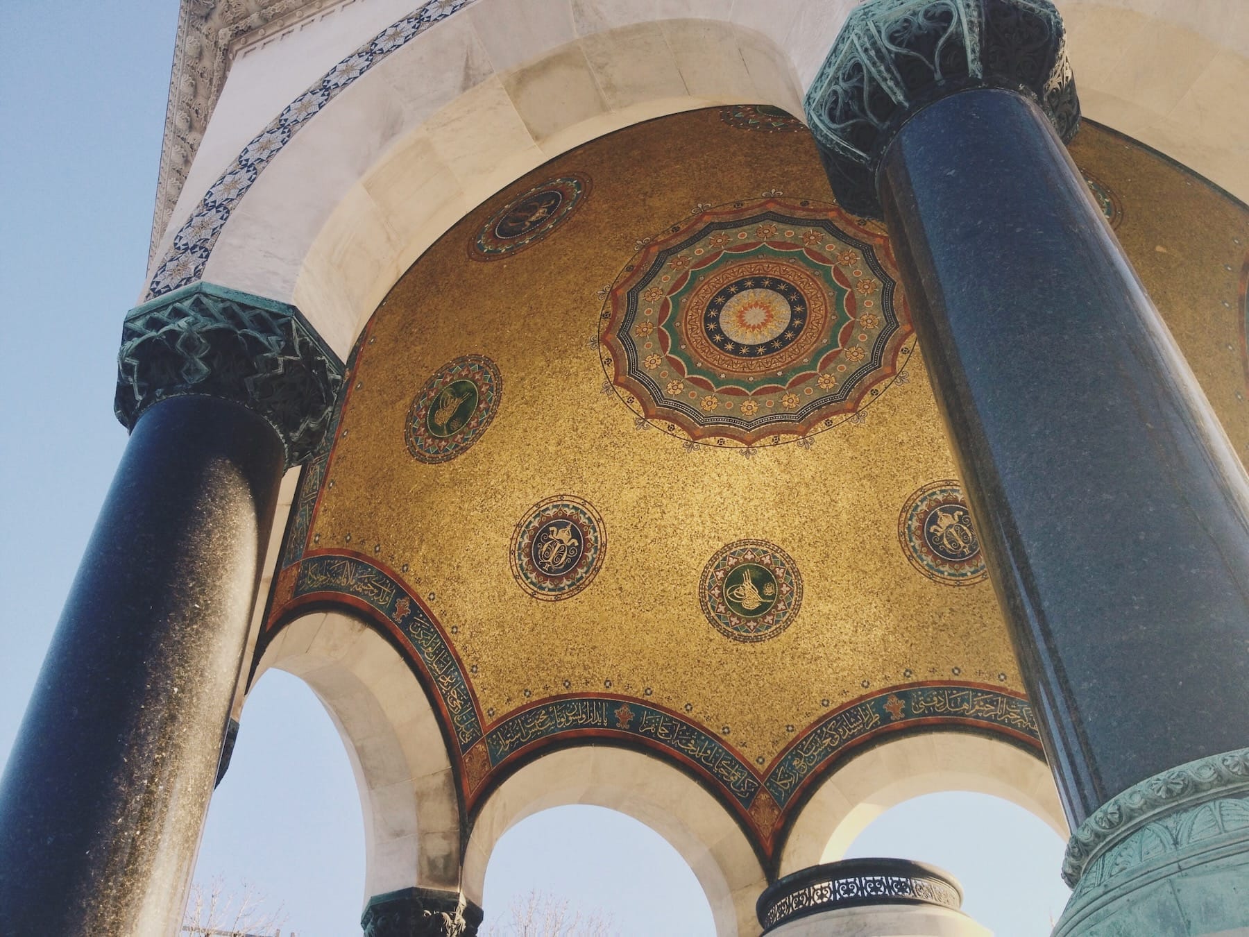 Fine Islamic ornament under a domed outdoor structure in Istanbul. Golds and colors glowing in ethereal light.