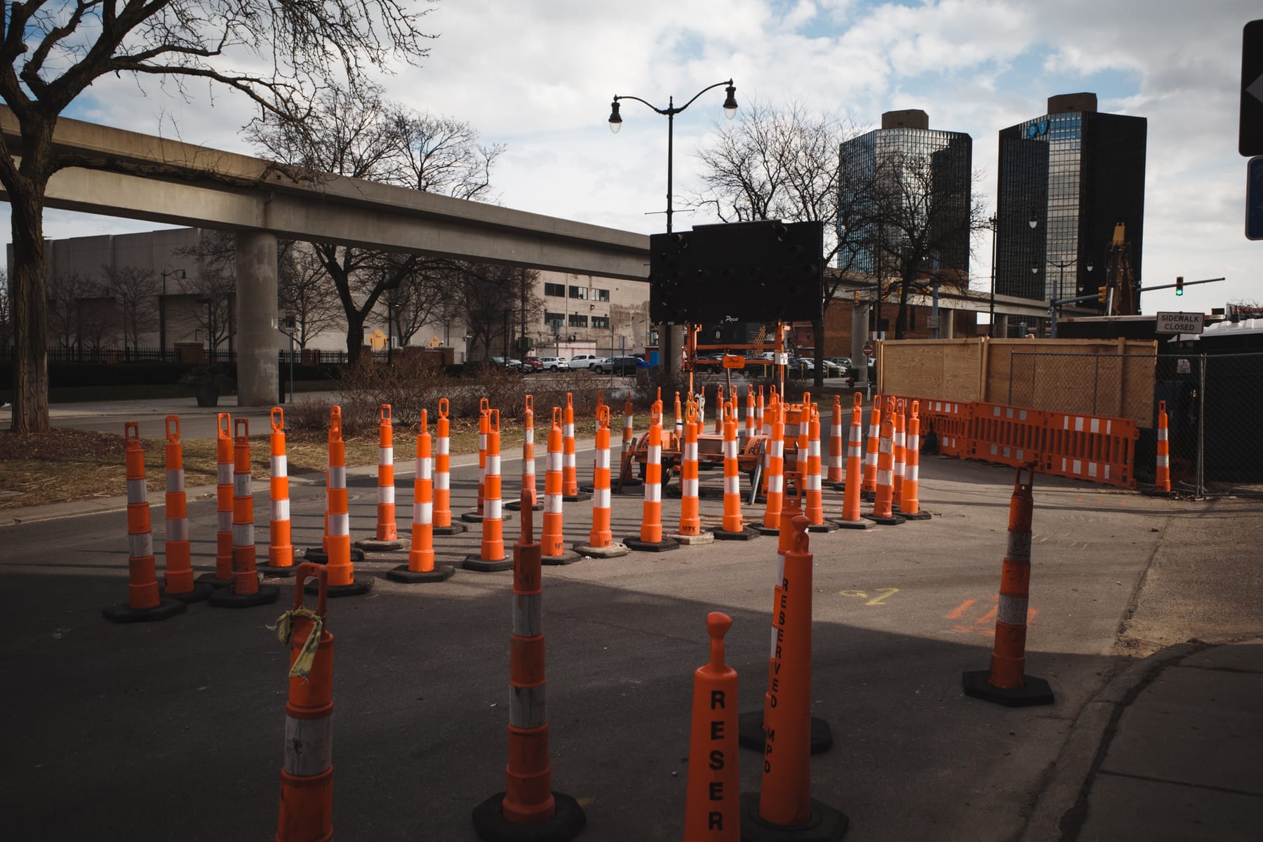 Triangular array of orange and white street pylons, part in shadow, part in sun.