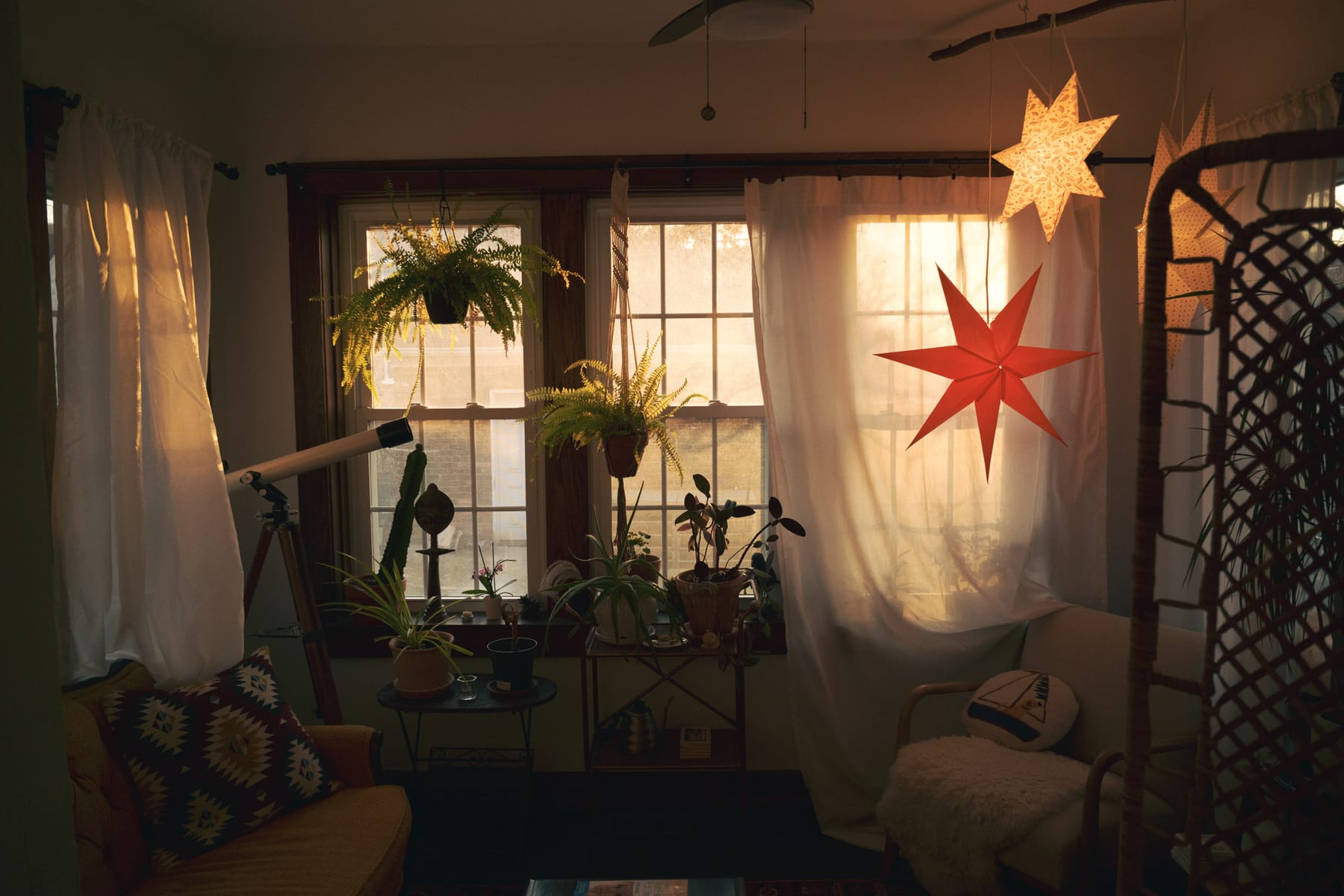 Sunroom at magic hour, warm light through windows and glowing star pendant lights