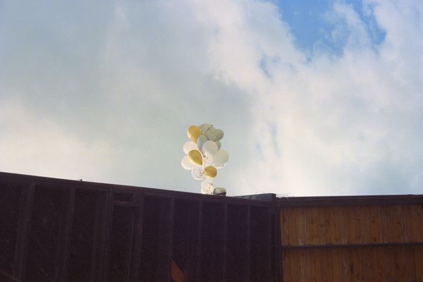Yellow, white, and robin's egg balloons strung to commercial rooftop.