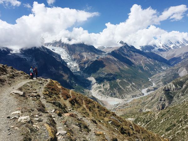 Hikers in the Himalayas, looking out over mountain valley.