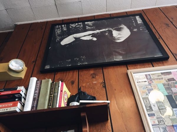 Looking up at framed black and white photo of Bob Dylan, against wood-paneled wall.