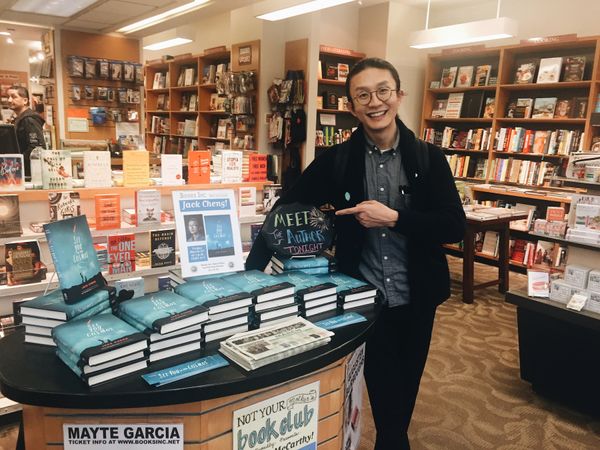 Me in the store, pointing to a stack of books.