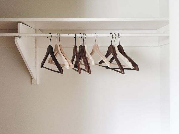 Empty hangers in empty white closet. Mix of blond and brown wood.
