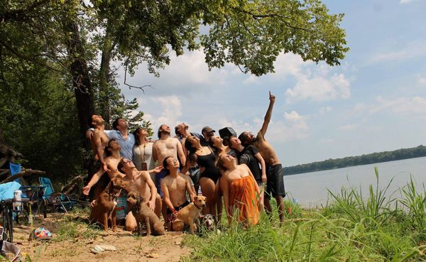 A bunch of weirdos (and three pups), eyes closed, pointing at the sun.