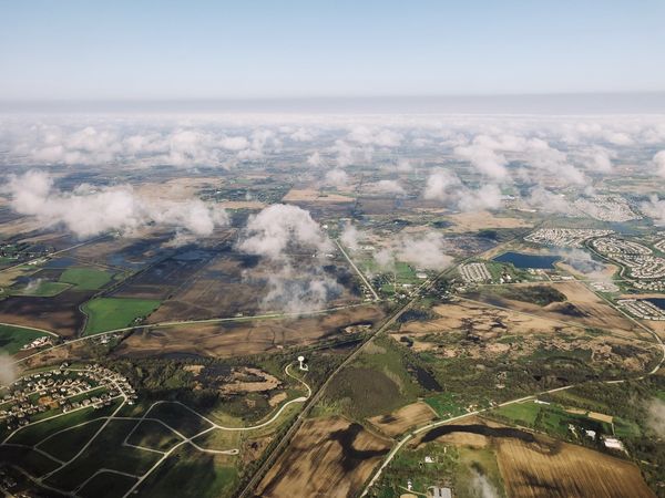 Photo from airplane window of fields spotted with clouds