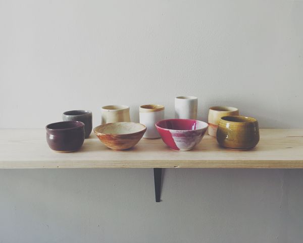 Bowls and cups, mostly browns, whites, and yellows, with one red bowl.