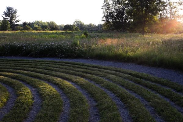 Sun setting on native prairie, beam over grassy labyrinth rings.