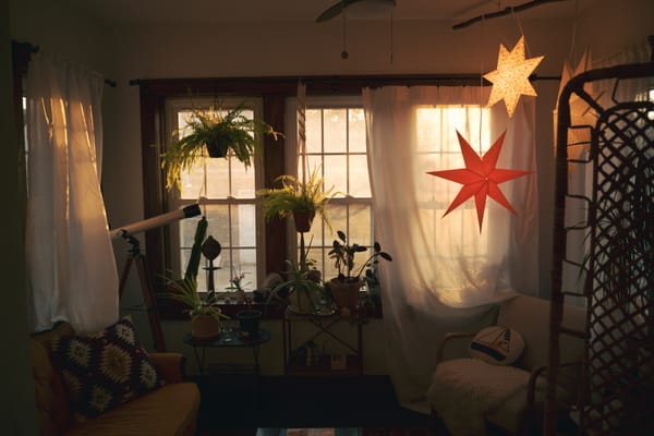 Sunroom at magic hour, warm light through windows and glowing star pendant lights